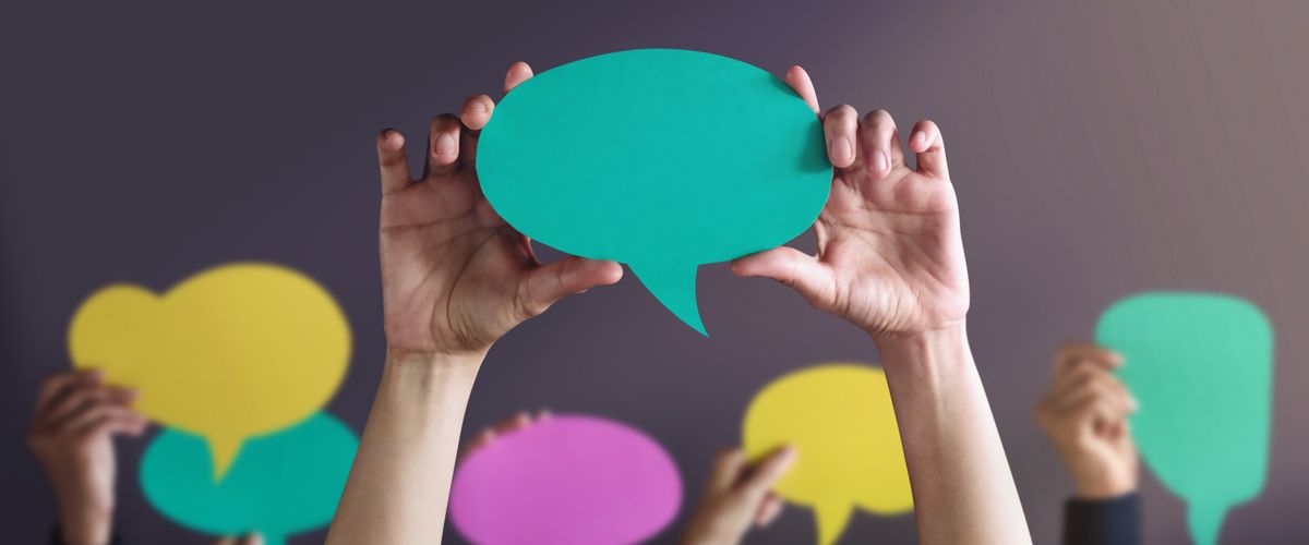 Students holding up speech bubbles made of colored construction paper