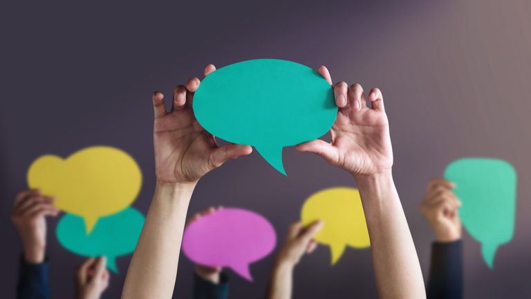 Students holding up speech bubbles made of colored construction paper