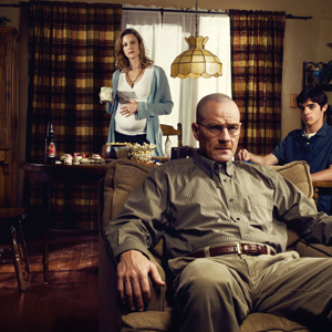 Breaking Bad character Walter White sits in a recliner with his family wife Skylar and son Walt Jr. in the background.