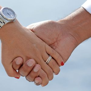 Detail photo of married couple holding hands