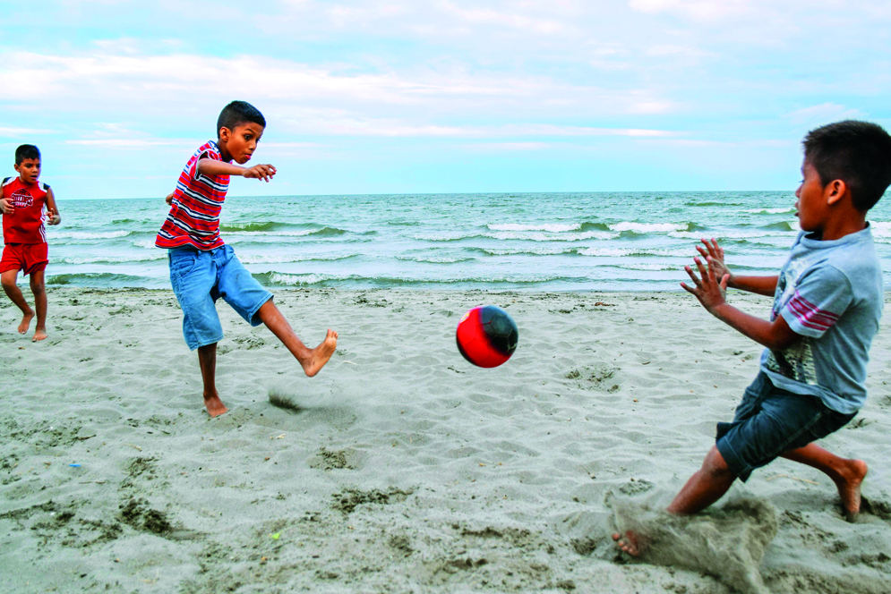 kids playing soccer on the beach