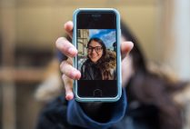 Lexi Herosian holding a phone with a photo of herself on it
