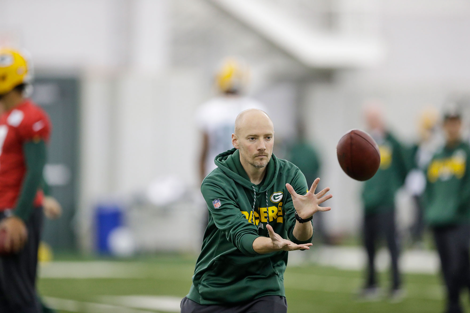 Adam Korzun, director of performance nutrition for the Green Bay Packers, catches a football during a Packers practice.