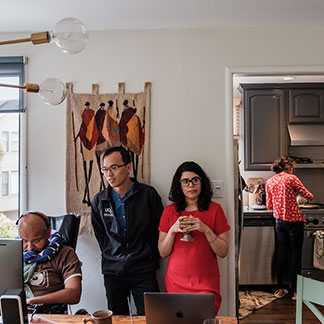 Craig Cloutier, Rahul Desikan, Iris Broce, and Chin Hong Tan work in Desikan's office while Desikan's wife Maya makes a meal in the kitchen.