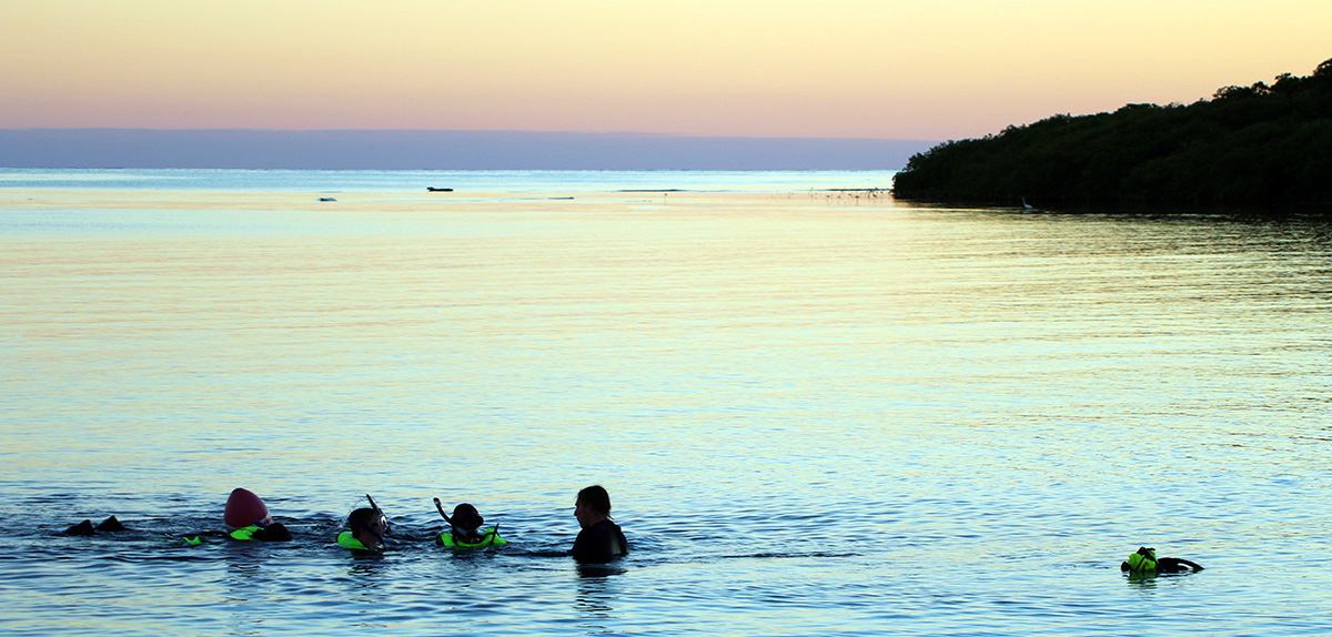 BU researchers scuba dive during a pink and blue sunset off the coast of Turneffe Atoll, Belize