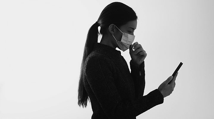 Woman looking at phone while wearing a face mask