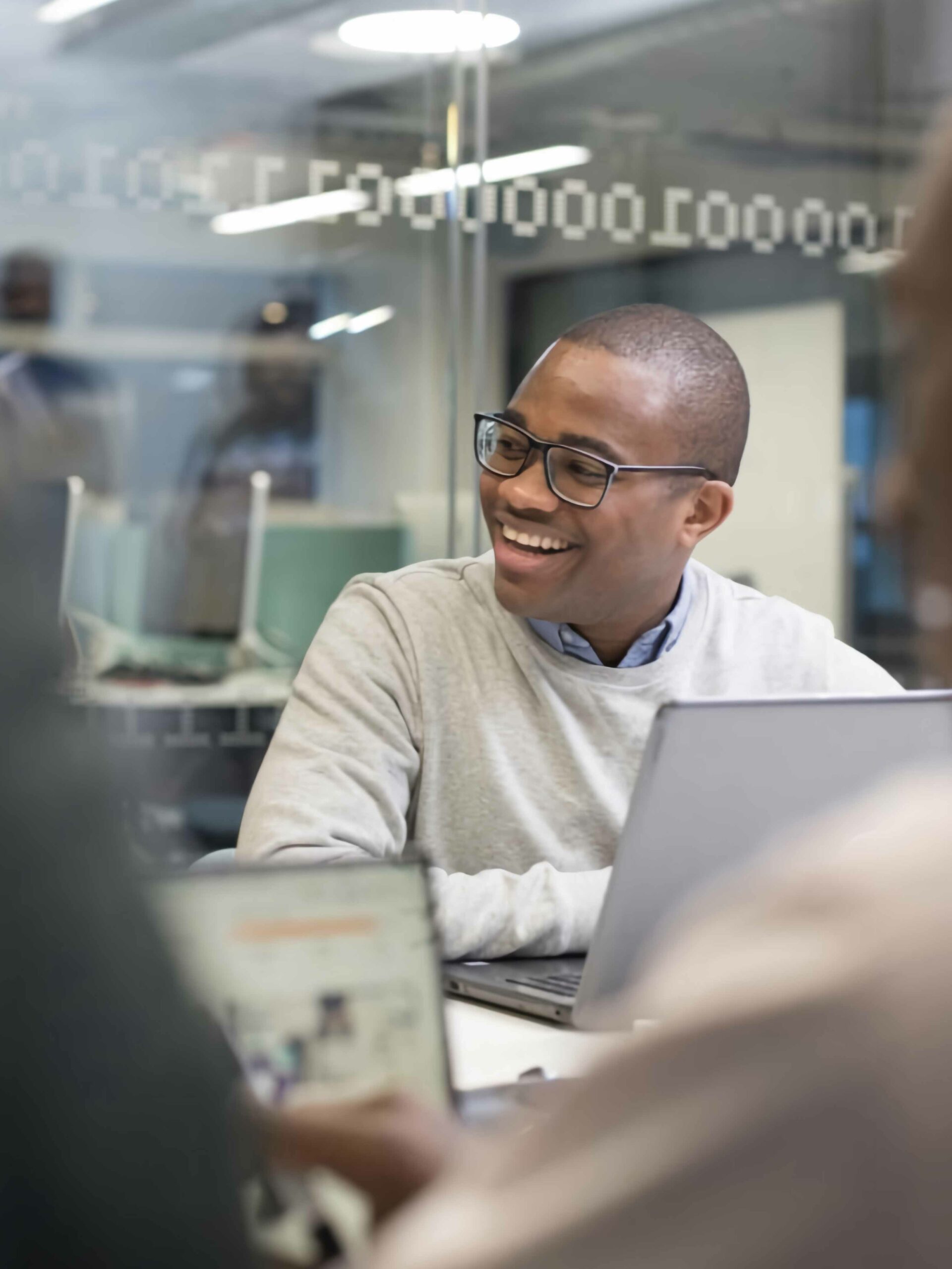 Photo of student working on a laptop with other students around