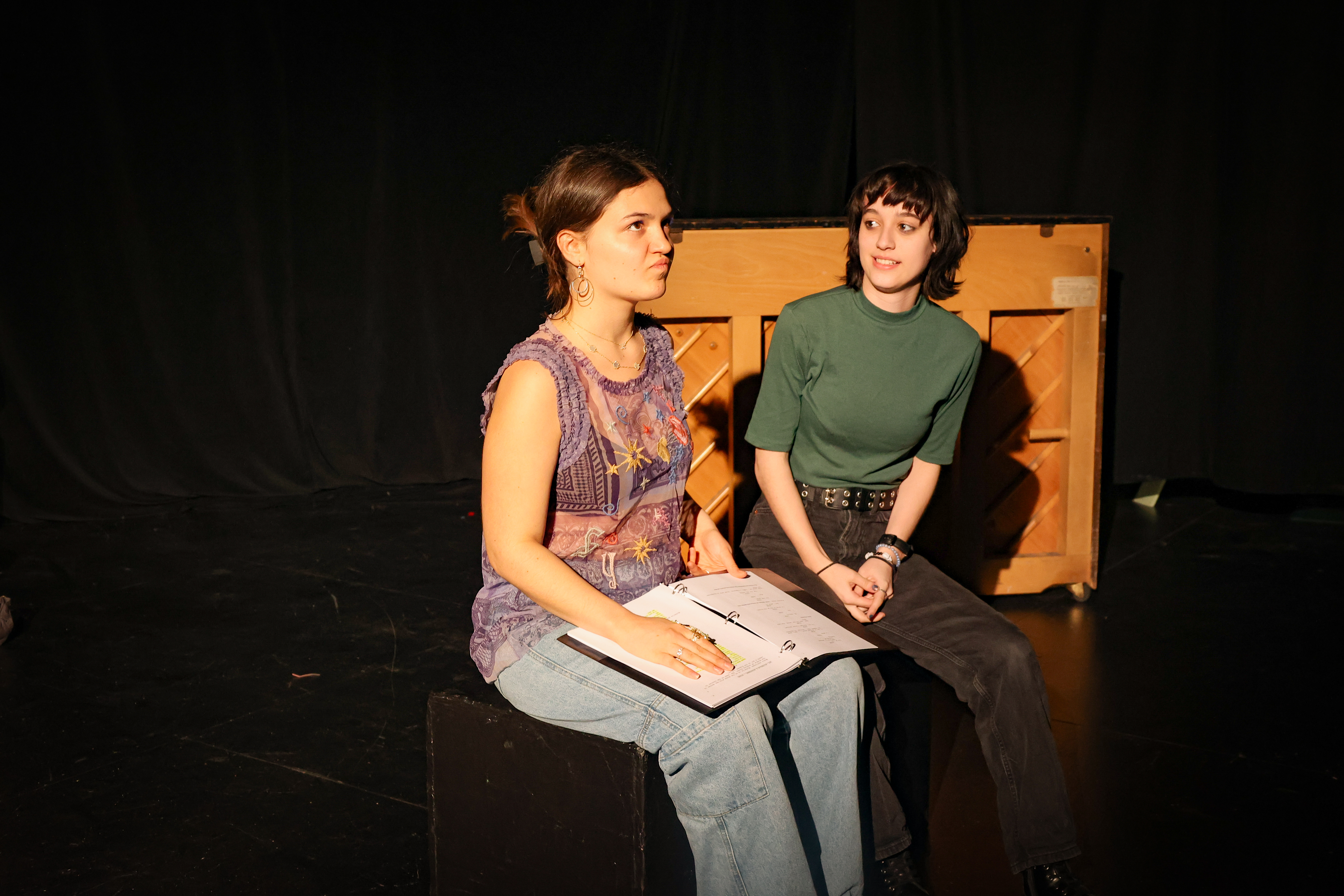 Two acting students reading scripts in a black box theatre