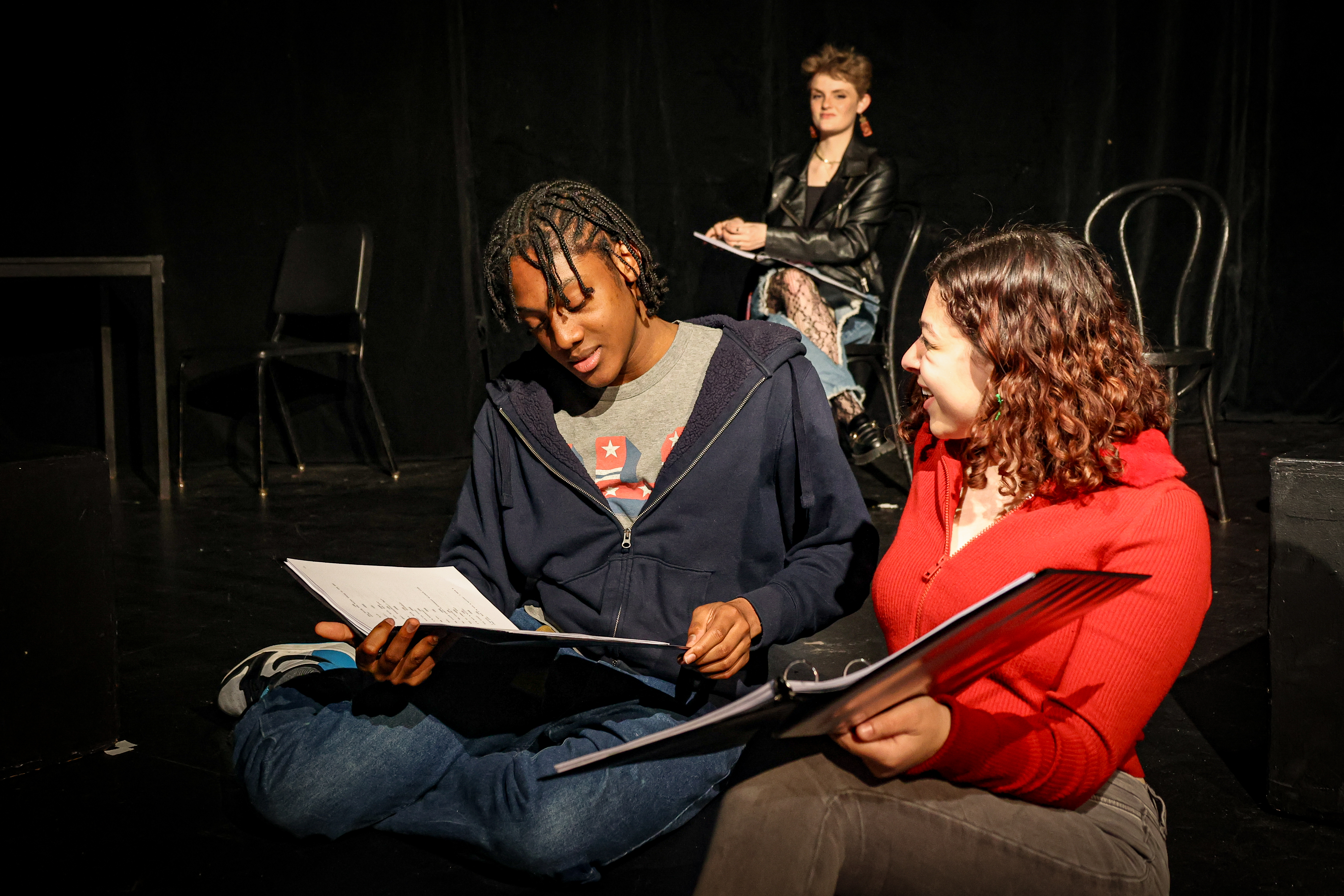 Two acting students reading scripts in a black box theatre