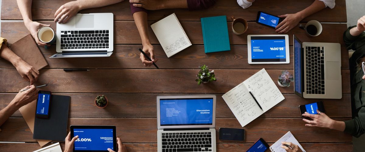 vertical shot of people sitting around a desk with computers