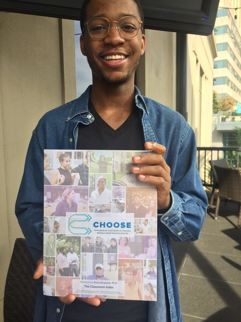 Jordan Williams holding a copy of the book he contributed to 