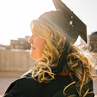 Young woman looking left wearing mortarboard.