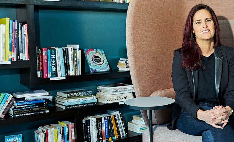 Colleen McCreary seated for smiling portrait in front of book shelf.
