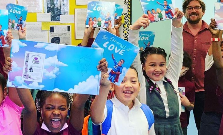 Group of young students smiling and holding up copies of a book titled "The Forecast Is Love."