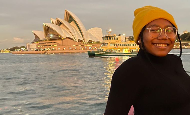 DaJanae Hester seated on a boat with the Sydney Opera House in the background.