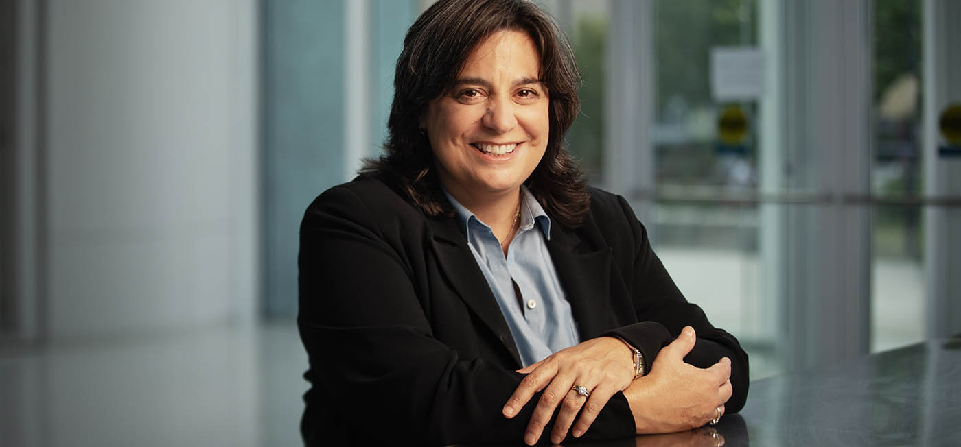 COM Dean Mariette DiChristina seated at a table with arms folded.