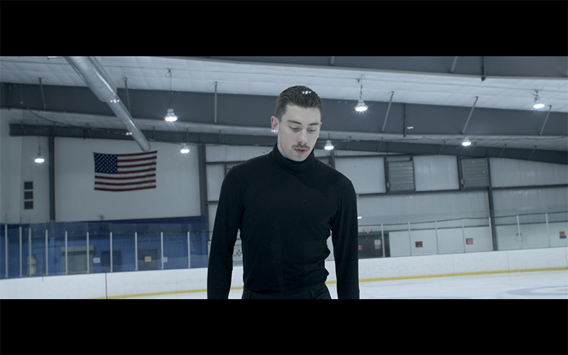Production still from Pas De Deux, showing a young man in an ice rink.