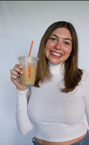 Carly smiling holding dunkin iced coffee