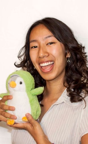 Open mouth smiling headshot holding stuffed penguin