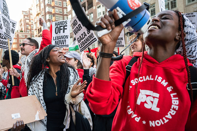 Young woman shouting into a megaphone, joined by other young protestors.