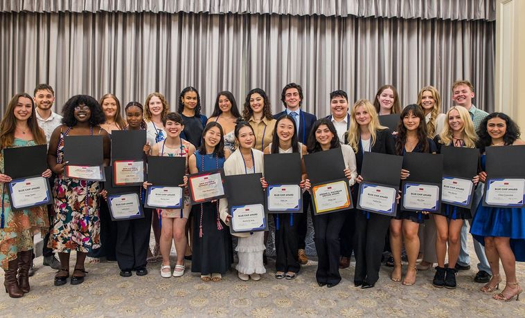 Students grouped in front of a curtain.