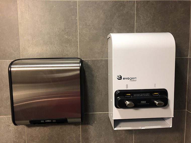 hand dry and menstrual product dispenser mounted to bathroom wall