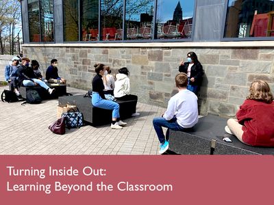 View from behind students from sitting on benches in front of the instructor and listening.