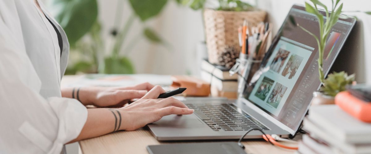 Laptop on a desk with a person's hands on the keyboard.