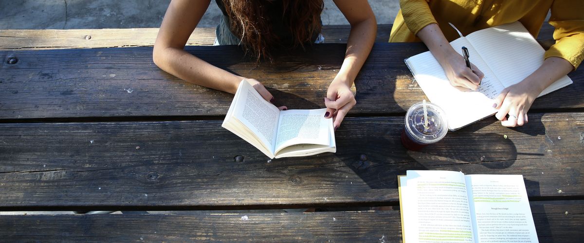 Overhead photo of two women and another person studying together at a wooden picnic table
