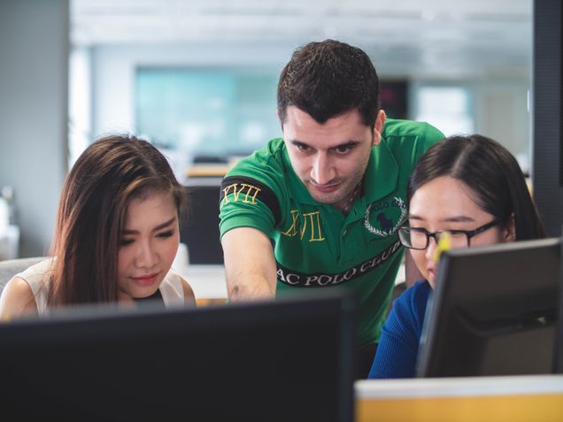 Group of people around a computer working together