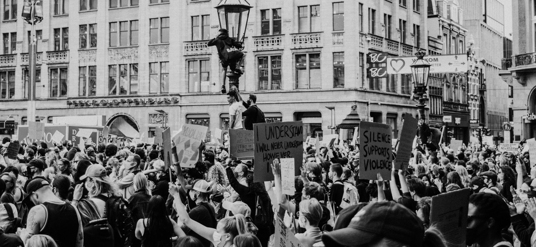 People in a crowd protesting with raised fists and poster signs
