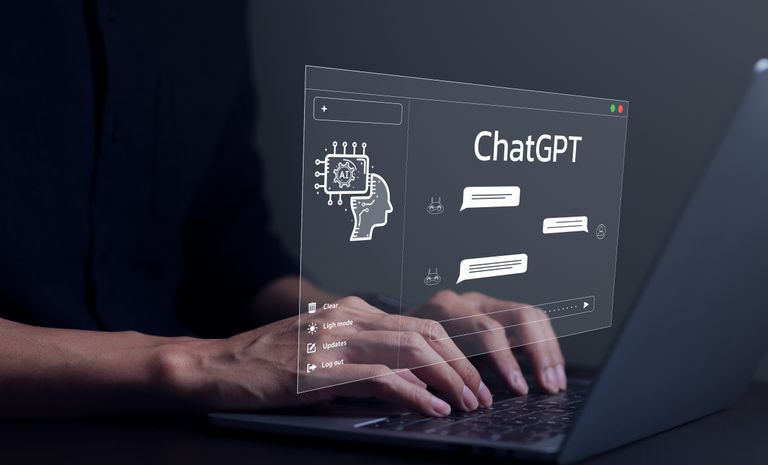 Hands typing on a laptop with the ChatGPT logo in a chat box above the keyboard