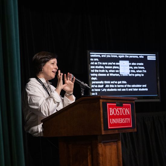 Lilach Mollick speaks during the Keynote next to a live captioning device