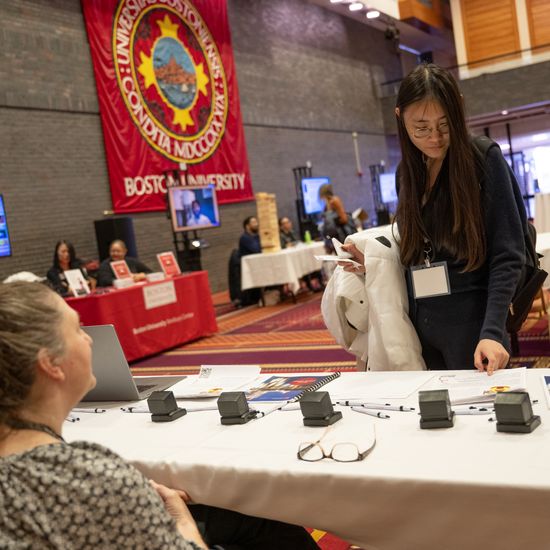 Dongpeng Huang visits a table and looks at their materials