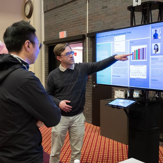 Attendees are listening to an e-poster board presentation.