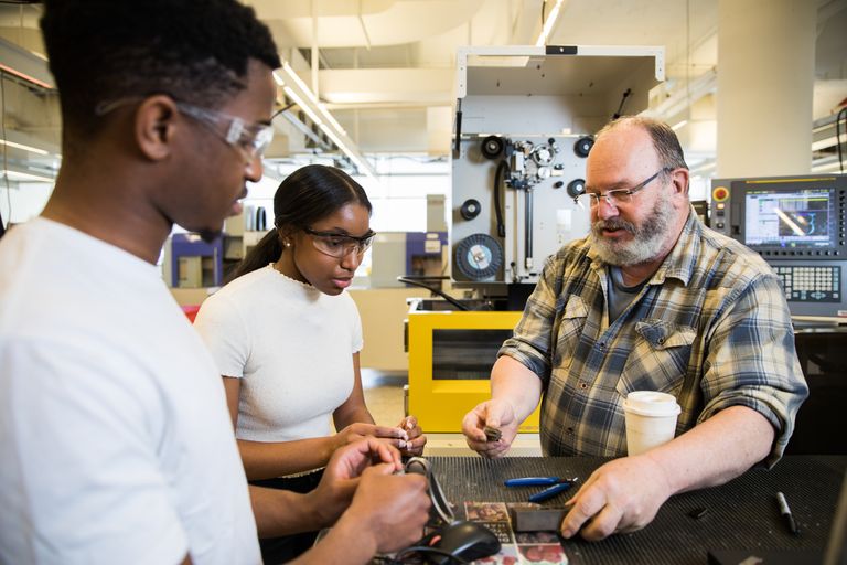 Two students receiving instructions from a faculty member in the robotics lab