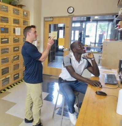 a student pointing off screen to show another student something, the front lockers of SILab are in the background