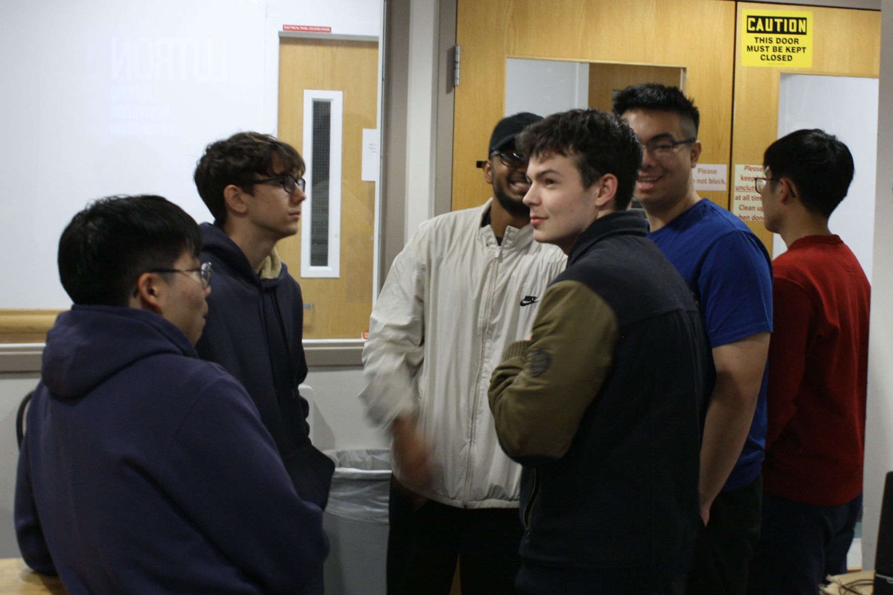 6 male ENG students grouped up and smiling while chatting