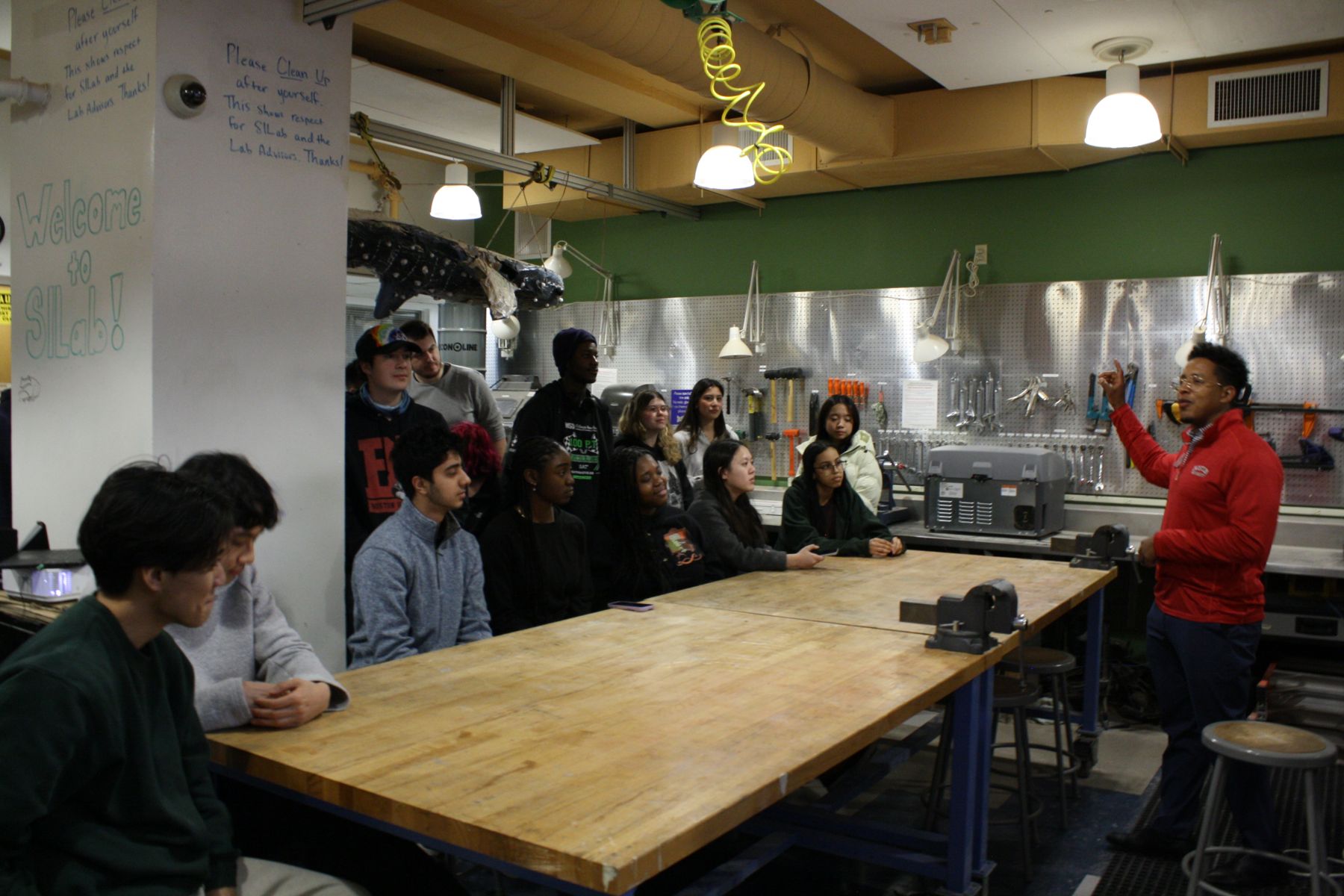large group of students clustered around long tables listening to presentation by Kevin from the ENG CDO