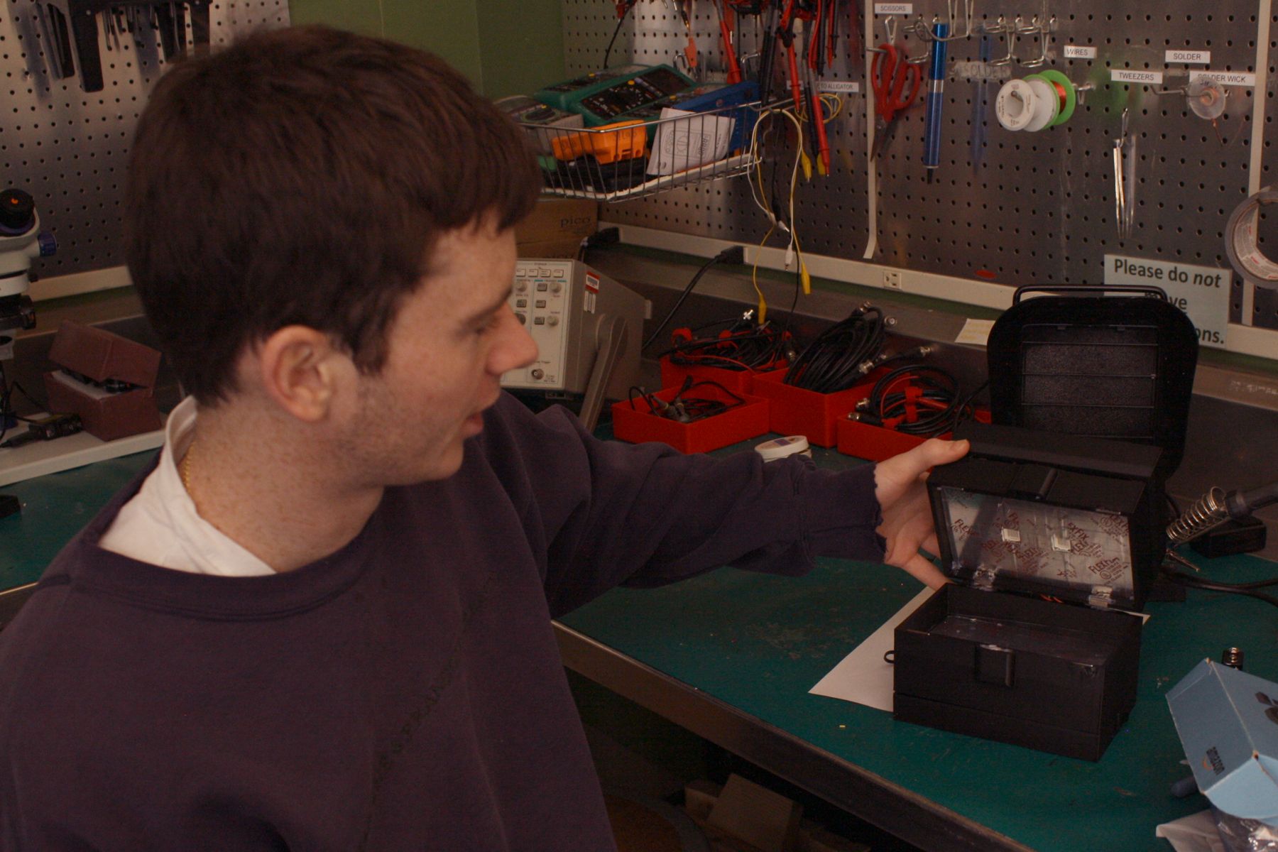 student showing off black box, which when opened shows a UV phone sterilizer