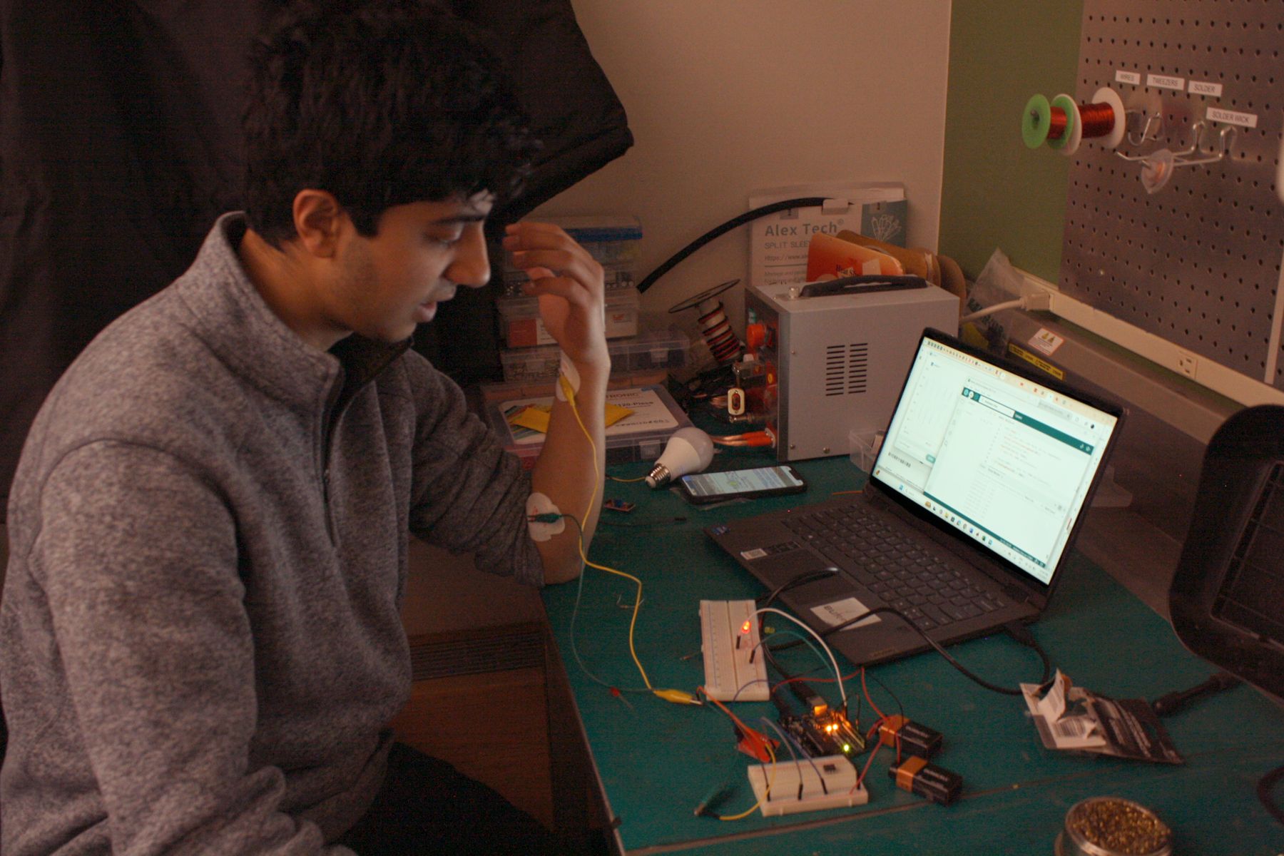 student demonstrates his muscle reactive lights by flexing his arm to turn on an LED