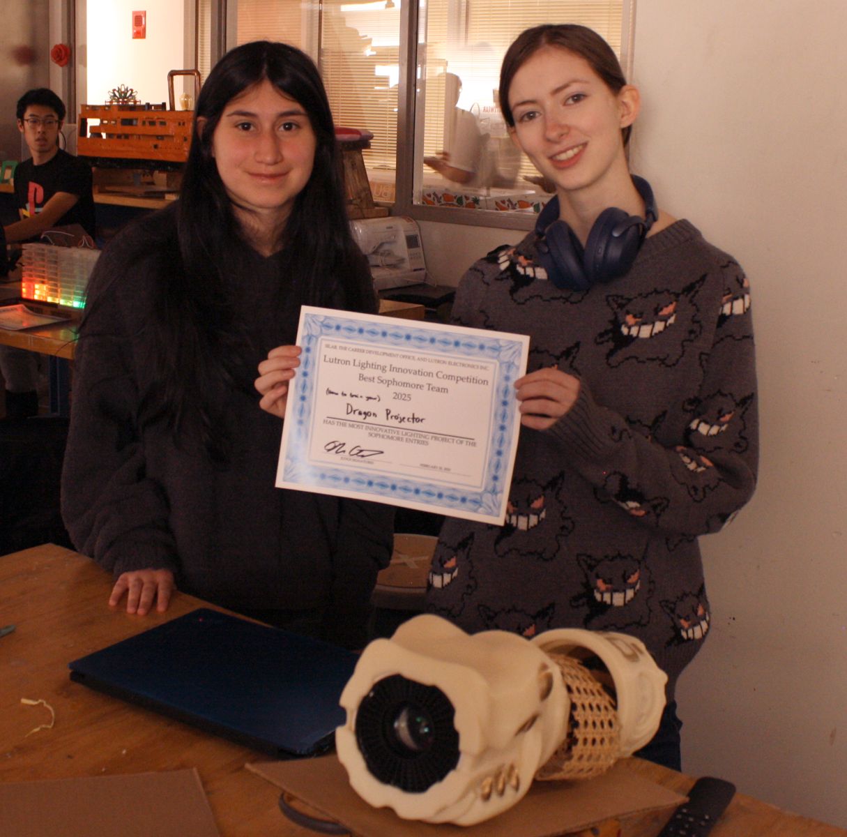 2 students with their project of a dragon shaped projector with their best sophomore project certificate