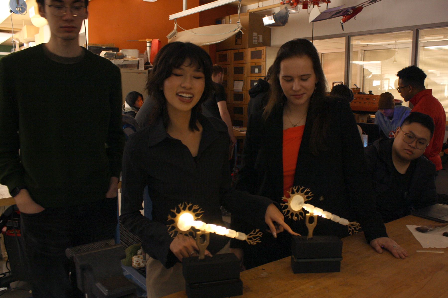 2 students pointing at their neuron shaped project that lights up based on sound input