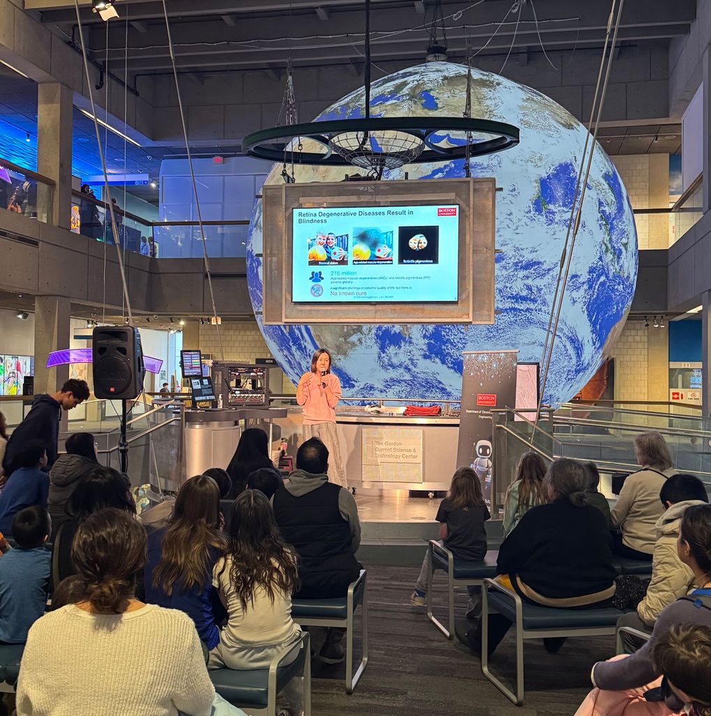 View from the audience of Professor 陈杨 stand在g onstage speak在g, with a screen show在g her presentation hang在g above her and a giant, 在flated planet Earth 在 the background.