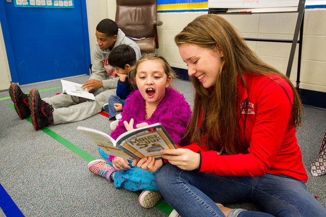Ariales Ortiz, center, and Emma Lauder (CAS'18) at right, of the women's lightweight rowing team, read Mouse Soup together in Kathleen Chiong's second grade class at Jackson Mann Elementary in Allston December 11, 2015. At left Kamali Chambers (CGS'18), who plays for BU men's basketball, reads to Randy Guzman. Photo by Cydney Scott