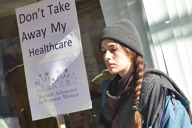 a woman holds a sign that says Don't Take Away My Healthcare outside of NY Representative Dan Donovan's office during a rally urging Republicans to preserve the Affordable Care Act, Staten Island, NY