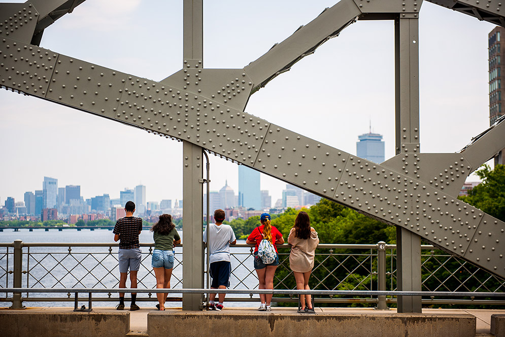 Pedestrians taking in view of downtown Boston from BU Bridge