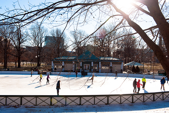 People Ice skating around Frog Pond on a sunny winter day.
