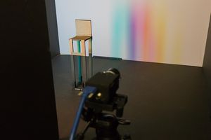A rainbow penumbra on a far wall is created by a bright scene displayed on an LCD monitor (left) and a chair (center).