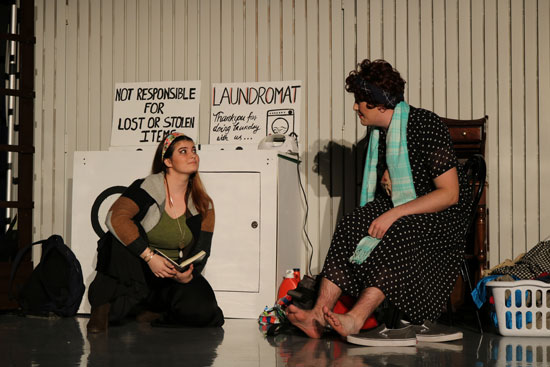 two people talking onstage with a set for a laundromat